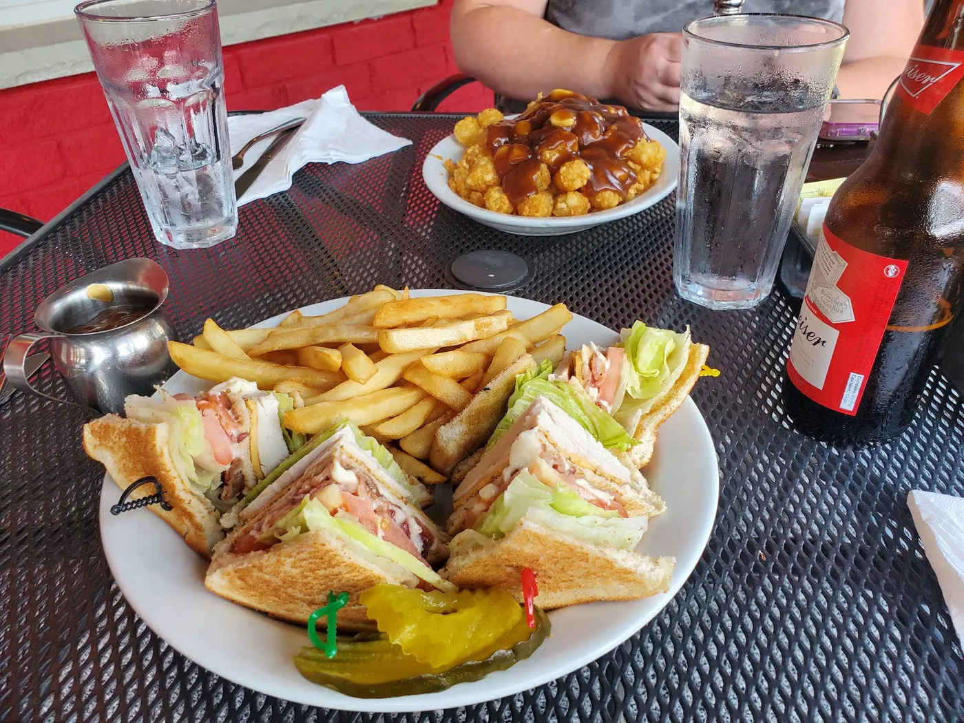 A clubhouse sandwich with fries and pickles