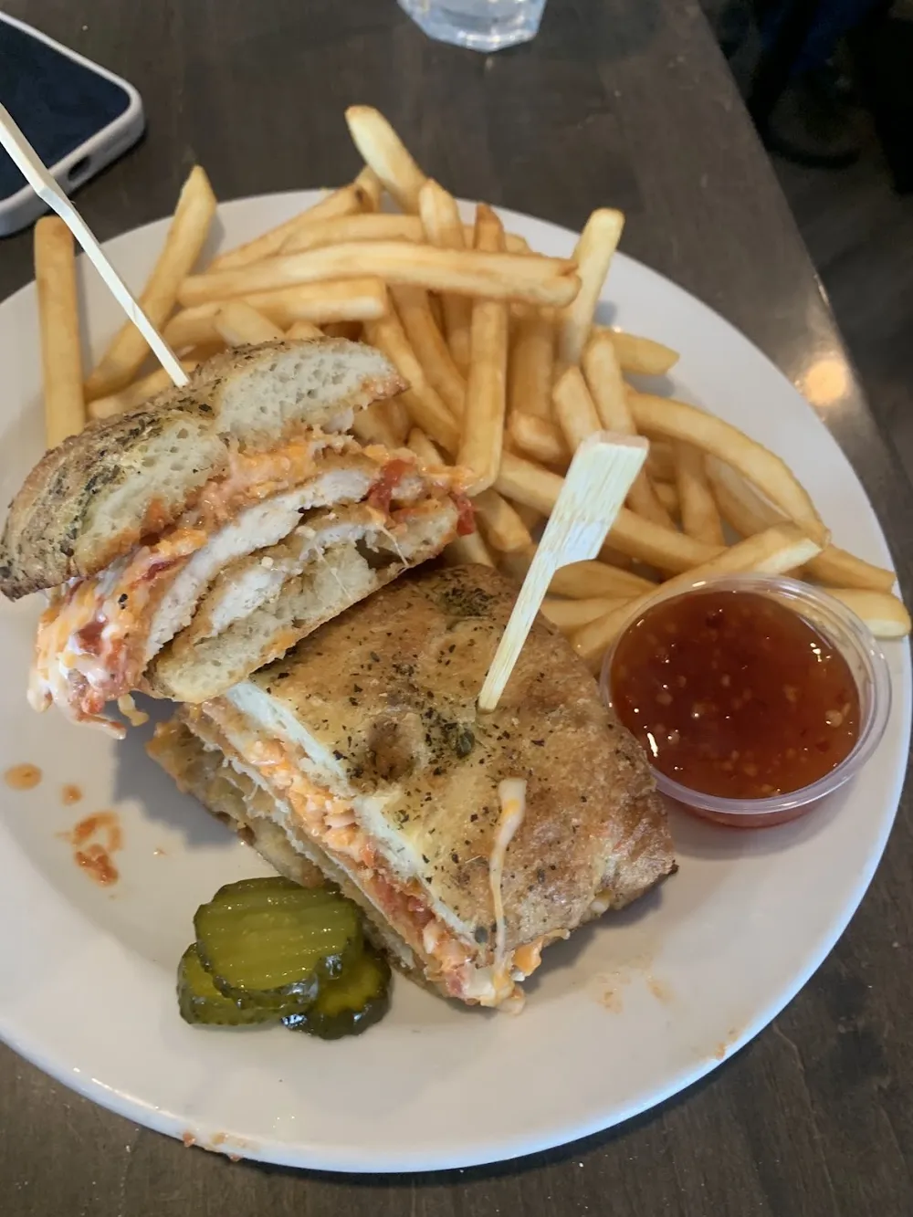 A toasted sandwich with fries and pickles